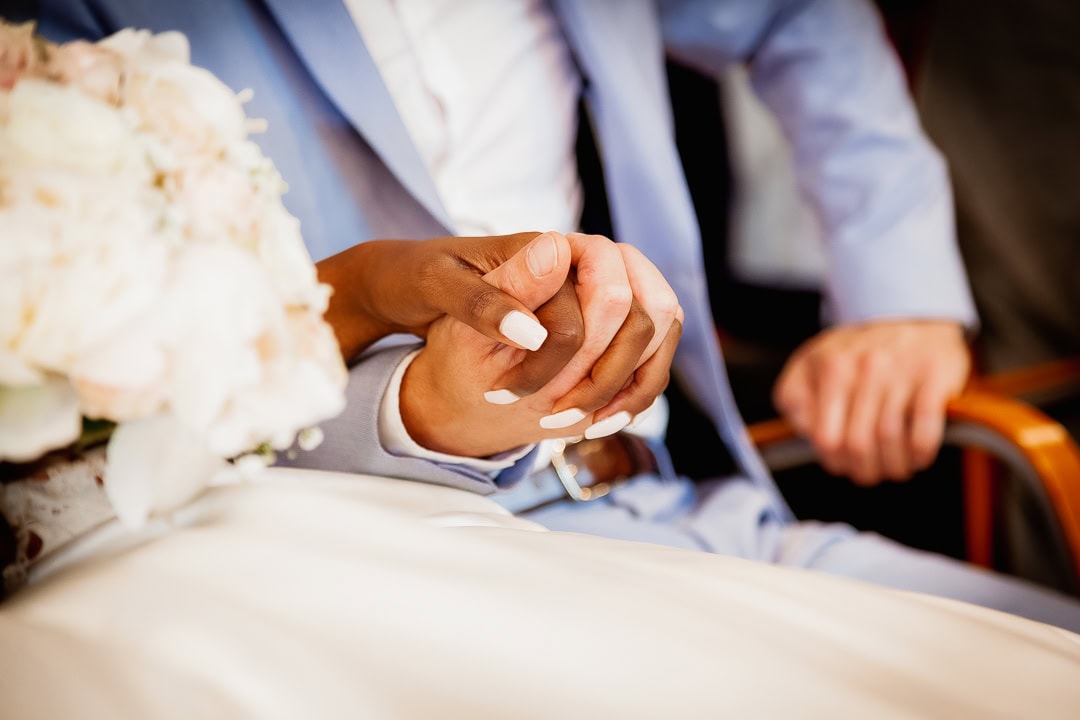 Photo symbolique de mariage à la mairie de Rennes : la main blanche et la main noire des mariés se rejoignent, capturant l'amour et la diversité en Bretagne.